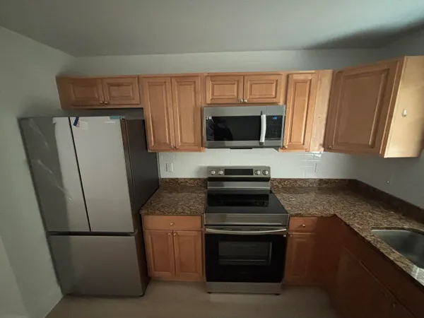 a kitchen with granite countertop a refrigerator stove and microwave