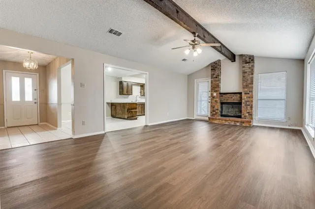 an empty room with wooden floor fireplace and windows