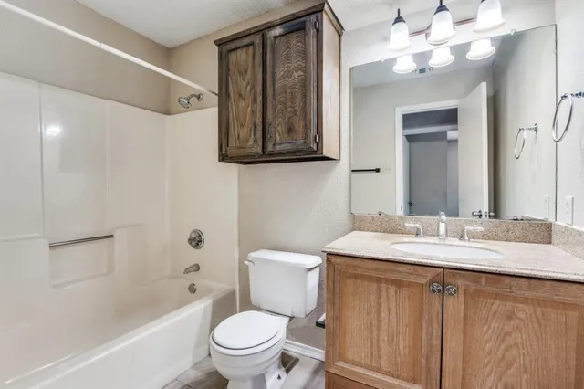 a bathroom with a granite countertop sink mirror vanity and toilet