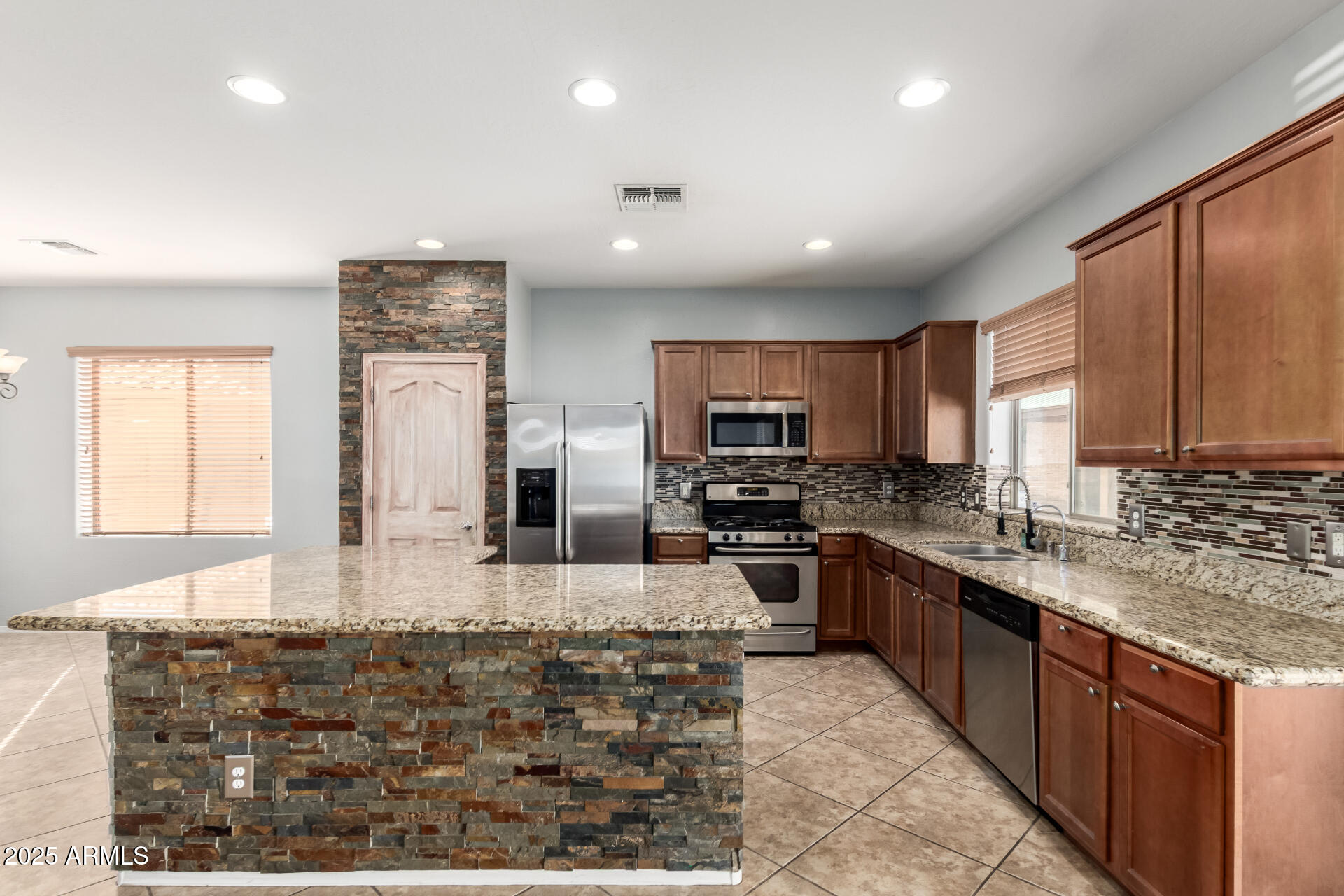 6756 South Seton Avenue Gilbert, AZ 85298 - Photo 7 of 37 a large kitchen with kitchen island granite countertop a large counter top stainless steel appliances a sink and cabinets