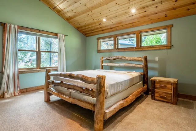 a bed sitting in a spacious bedroom next to a window