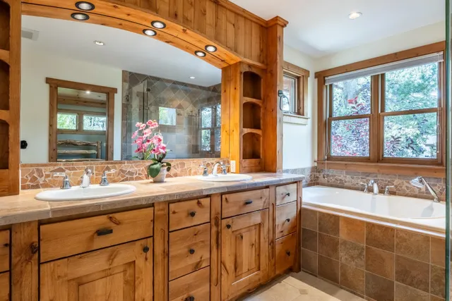 a bathroom with a sink mirror and a bathtub next to a window