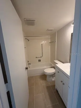 a bathroom with a granite countertop white toilet a sink and shower