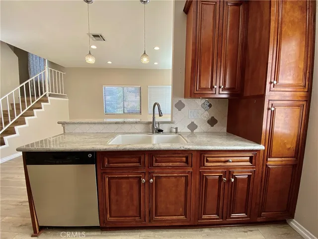 a sink sitting inside of a kitchen with granite countertop wooden cabinets