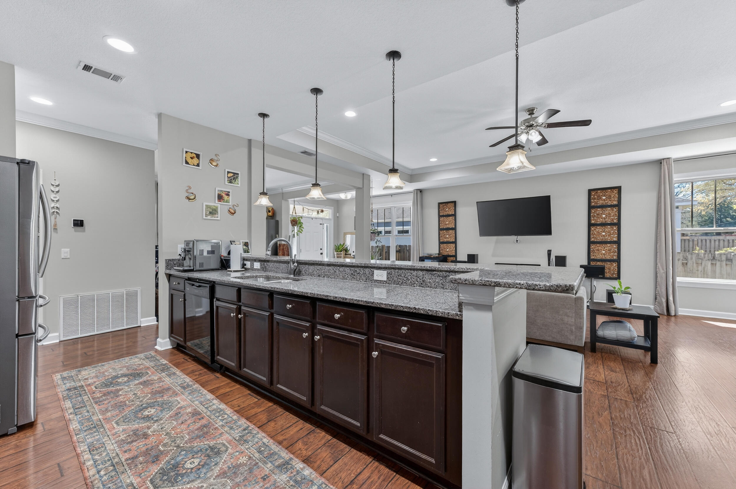 6022 Hidden Valley Road Crestview, FL 32539 - Photo 25 of 60 a large kitchen with stainless steel appliances kitchen island granite countertop a table chairs and a wooden floor