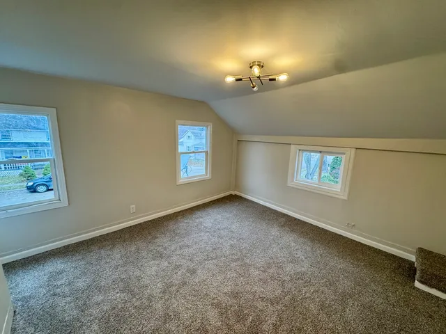 en empty room with windows and chandelier fan