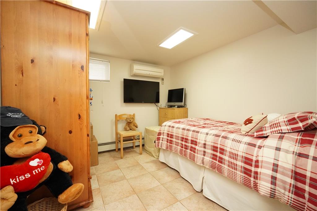 1463 84th Street Brooklyn, NY 11228 - Photo 22 of 30 a bedroom with a bed and flat tv screen on the dresser