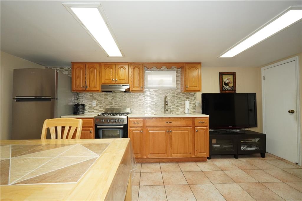 1463 84th Street Brooklyn, NY 11228 - Photo 26 of 30 a kitchen with granite countertop a refrigerator and a stove top oven