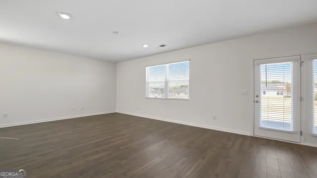 a view of an empty room with wooden floor and window