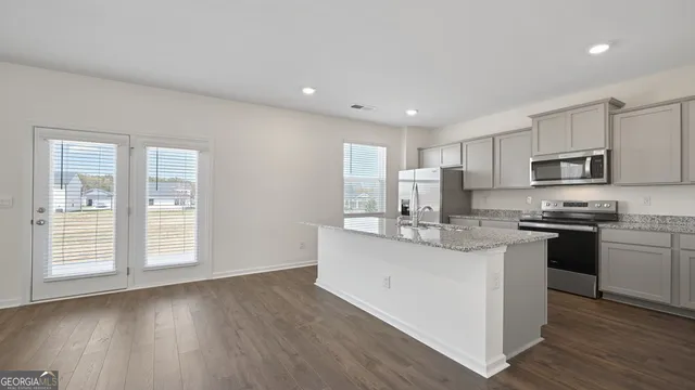 a view of a kitchen with kitchen island a sink wooden floor and a refrigerator