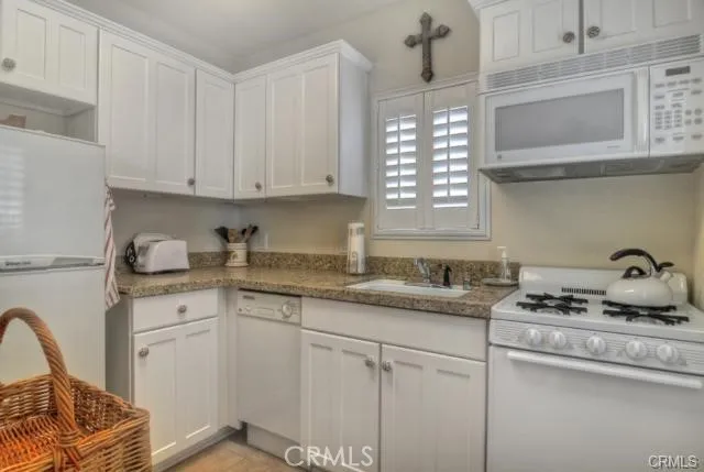 a kitchen with granite countertop white cabinets and window