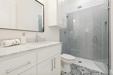 a bathroom with a granite countertop sink a toilet and shower