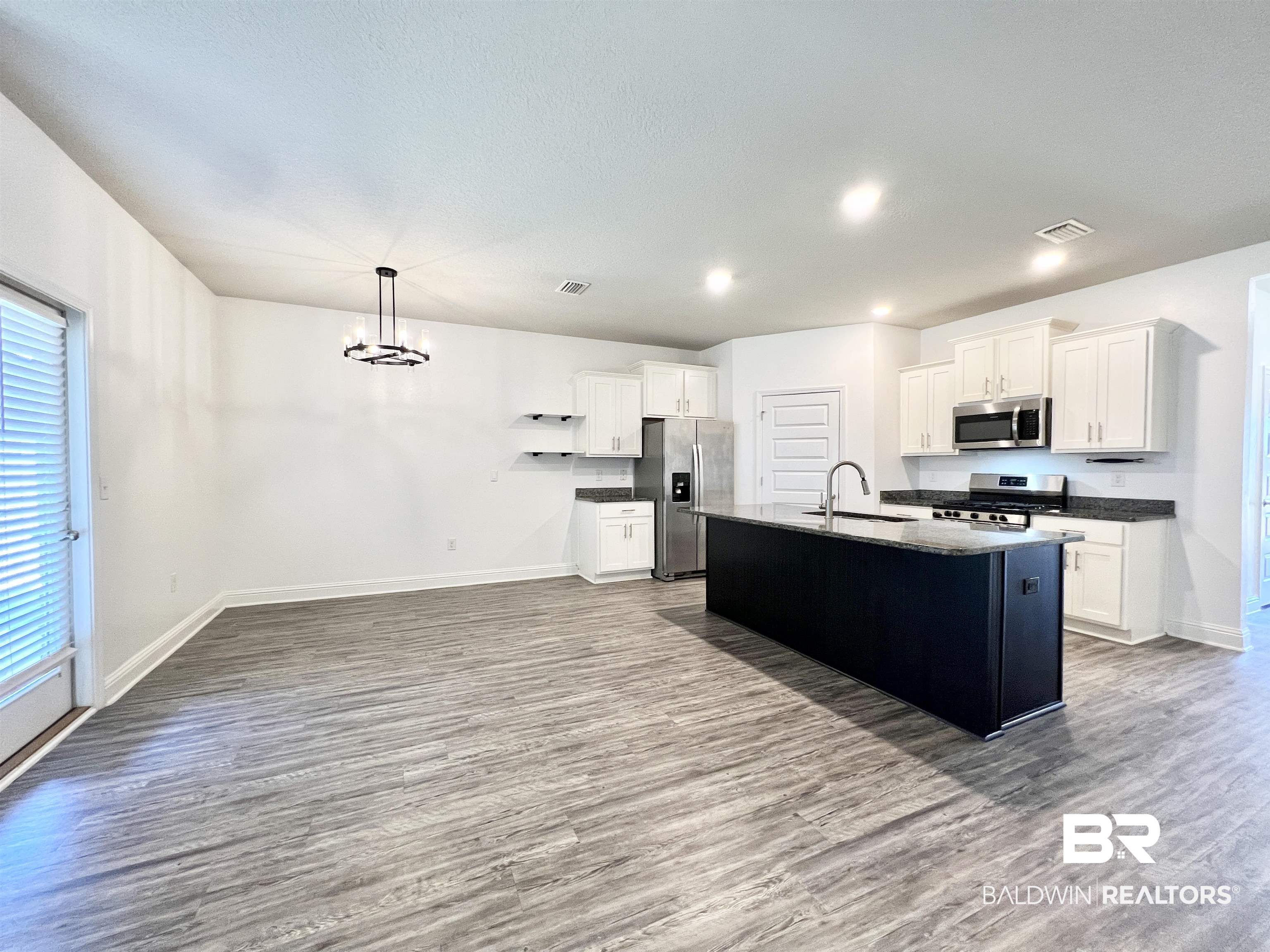 24785 Slater Mill Road Daphne, AL 36526 - Photo 2 of 46 Kitchen with a kitchen island with sink, white cabinetry, stainless steel appliances, and wood-type flooring