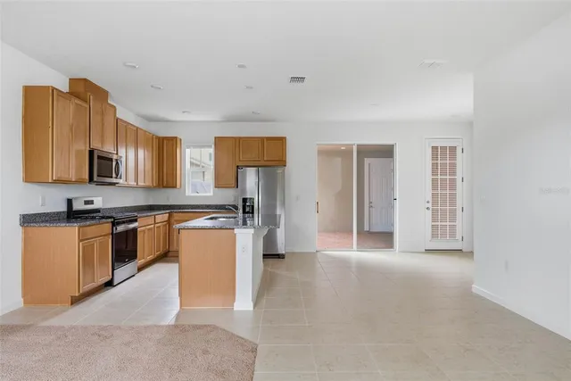 a kitchen with stainless steel appliances granite countertop a refrigerator a sink a stove a microwave and island