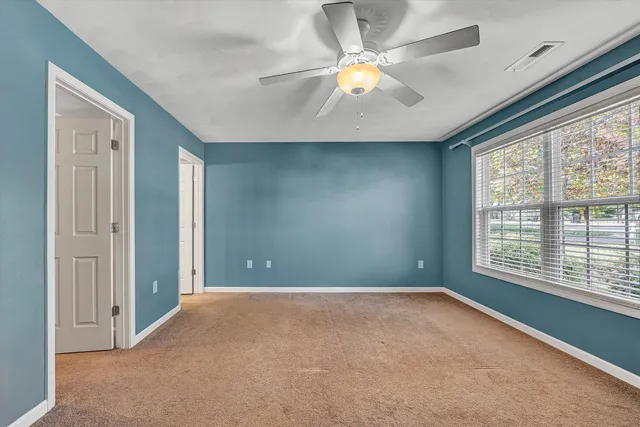 a view of an empty room with chandelier fan