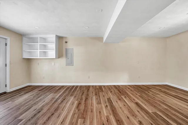 a view of an empty room with wooden floor and window