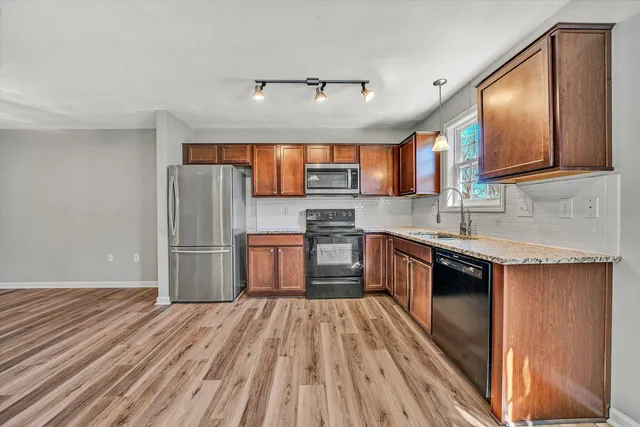 a kitchen with stainless steel appliances granite countertop a refrigerator a sink dishwasher a stove with wooden cabinets and floor