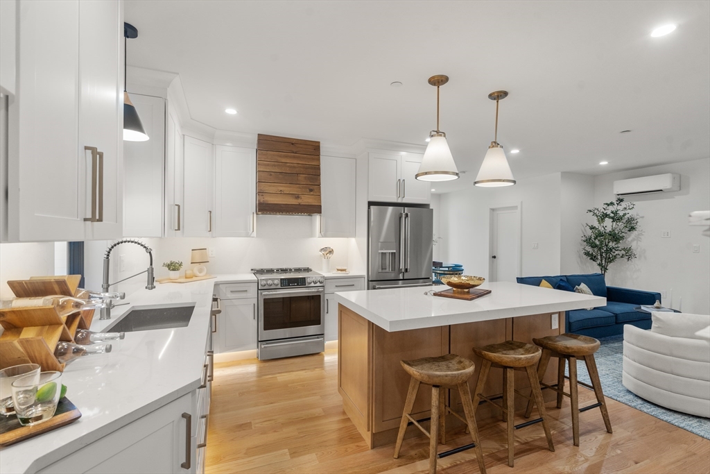9 Sydney Street, Unit 4 Boston, MA 02125 - Photo 1 of 23 a kitchen with stainless steel appliances kitchen island granite countertop a sink a stove a dining table and chairs