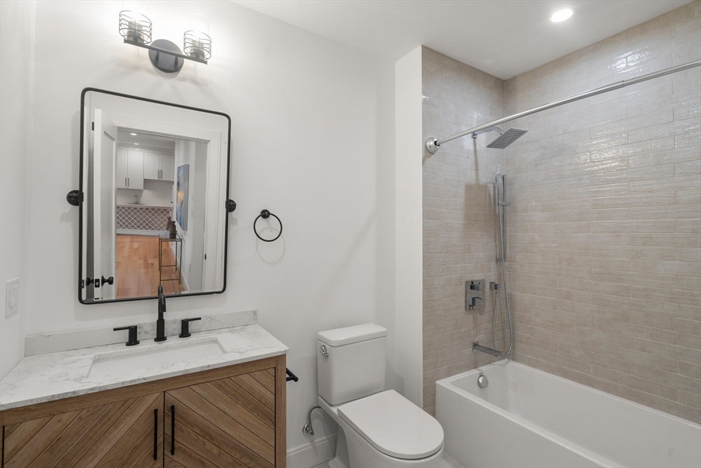 9 Sydney Street, Unit 4 Boston, MA 02125 - Photo 14 of 23 a bathroom with a bathtub shower sink vanity mirror and toilet