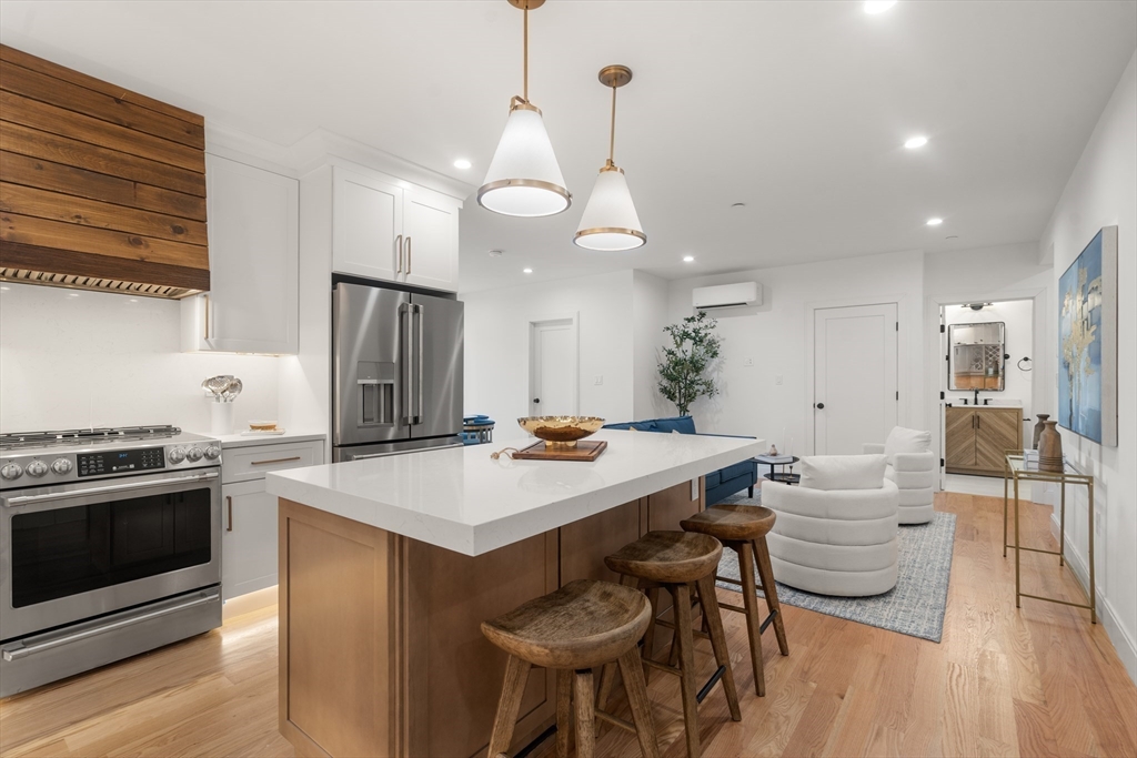 9 Sydney Street, Unit 4 Boston, MA 02125 - Photo 4 of 23 a kitchen with stainless steel appliances a stove a table chairs and a refrigerator