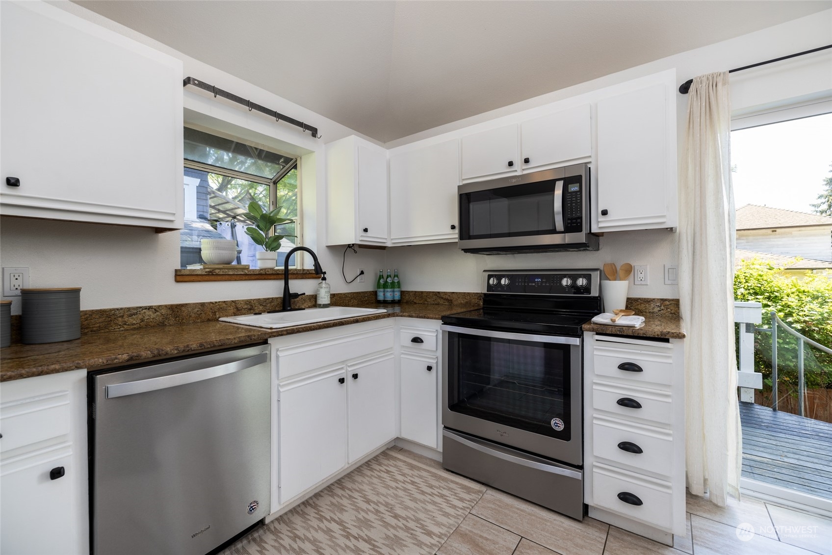 2131 North 88th Street Seattle, WA 98103 - Photo 15 of 28 a kitchen with granite countertop white cabinets white appliances a sink and a window