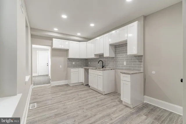 a large white kitchen with white cabinets and wooden floor