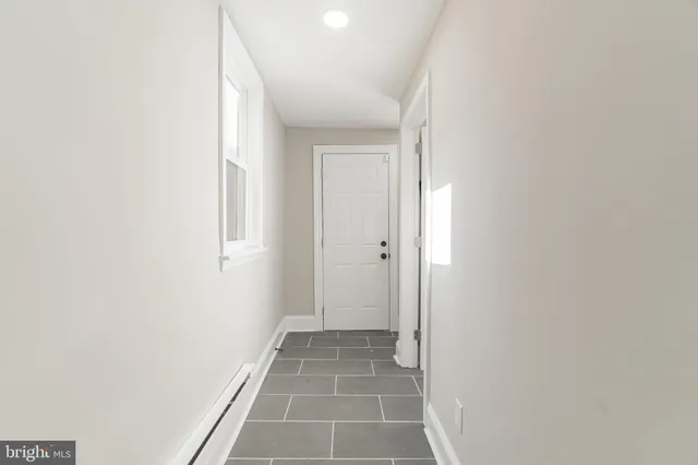 a view of a hallway with wooden floor and a bathroom