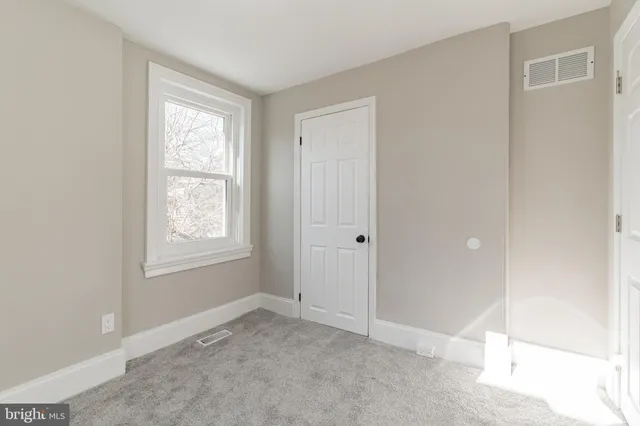 a view of an empty room with window and closet area