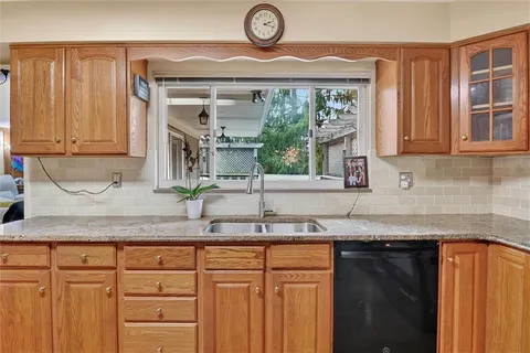 a kitchen with granite countertop stainless steel appliances a sink and cabinets