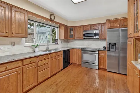 a kitchen with granite countertop a sink stainless steel appliances and cabinets