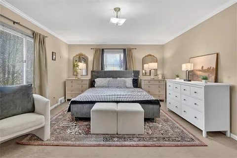 a spacious bedroom with a bed a mirror and windows