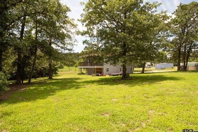 a view of a swimming pool with lawn chairs and large trees
