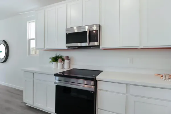 a kitchen with stainless steel appliances granite countertop white cabinets a microwave a sink and a white wooden cabinets