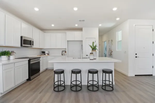 a kitchen with stainless steel appliances granite countertop a table chairs sink and cabinets