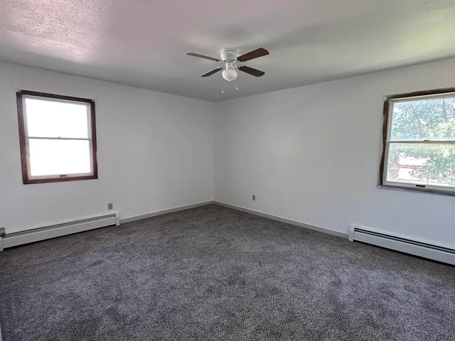 an empty room with a window and a ceiling fan