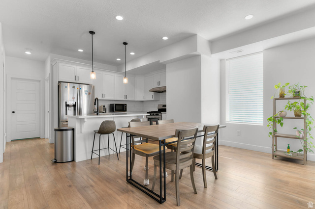 8307 Durham Street Sandy, UT 84070 - Photo 5 of 29 Open-concept kitchen and dining area featuring light wood-finish flooring, white cabinetry, stainless steel appliances, and recessed lighting