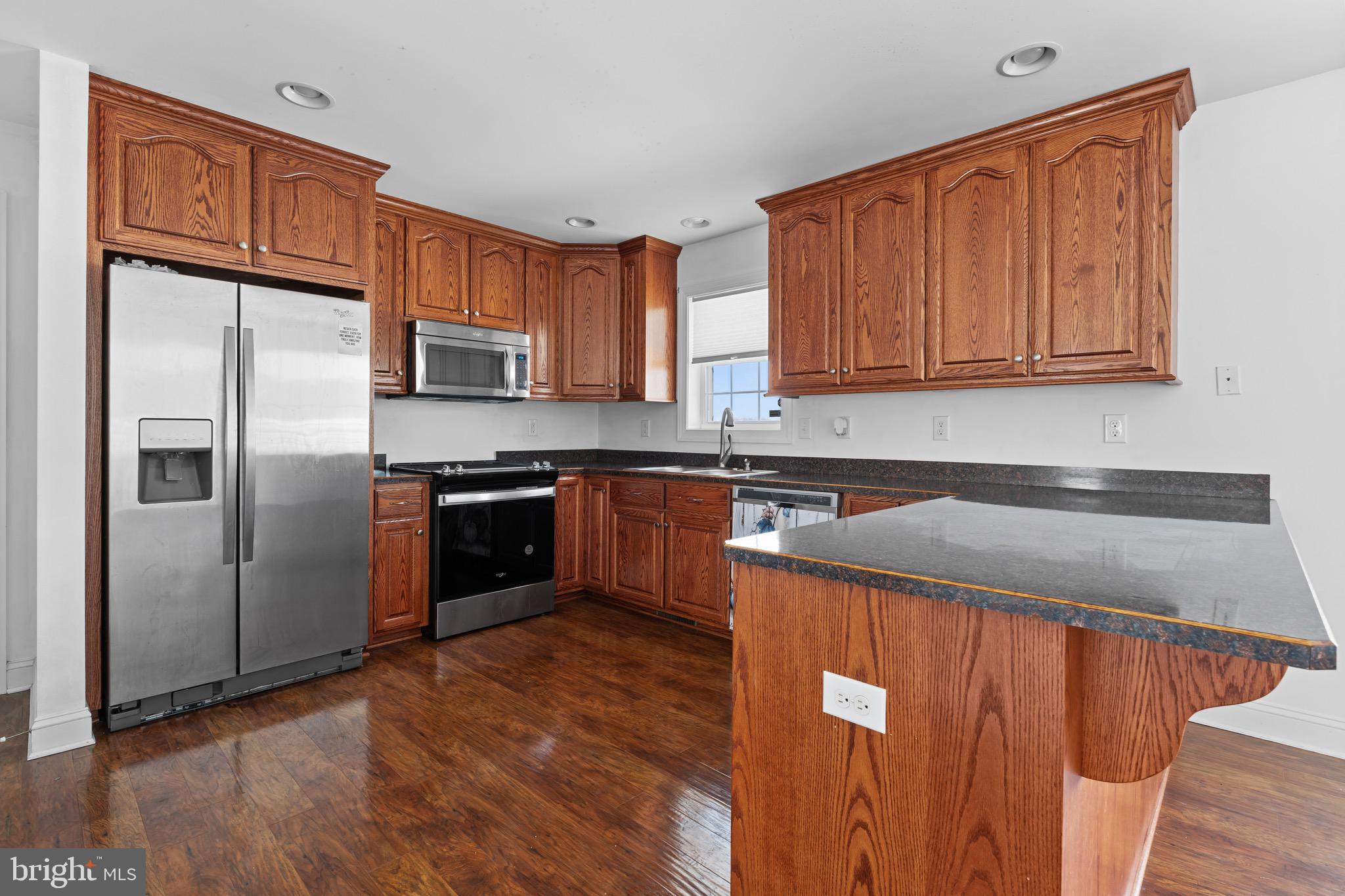 7180 Shawnee Road Milford, DE 19963 - Photo 3 of 20 a kitchen with stainless steel appliances granite countertop a refrigerator a sink dishwasher and wooden cabinets with wooden floor