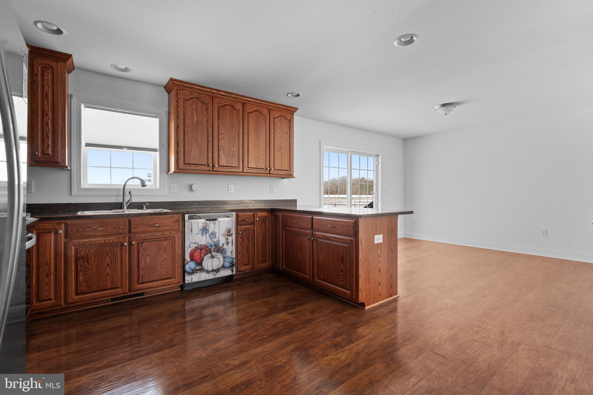 7180 Shawnee Road Milford, DE 19963 - Photo 4 of 20 a kitchen with granite countertop a stove a sink dishwasher and a microwave oven with wooden floor