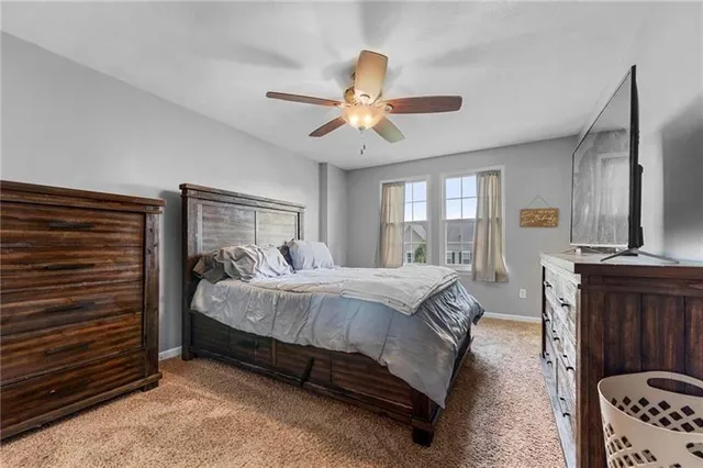 a spacious bedroom with a bed a dresser and a chandelier