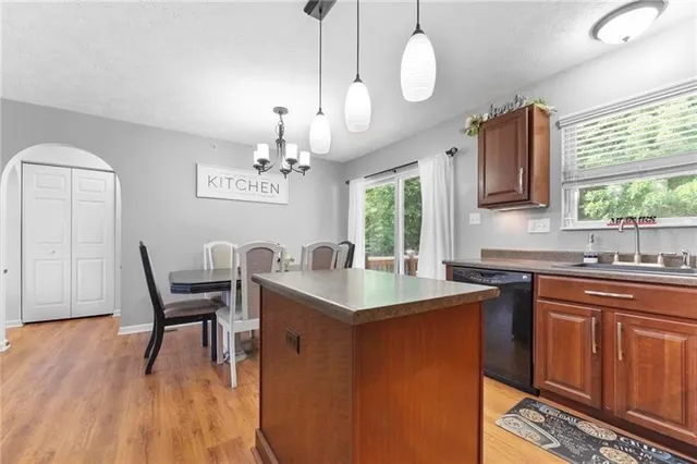 a dining hall with granite countertop a stove a sink a dining table and chairs with wooden floor