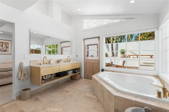 a spacious bathroom with a tub double vanity and window