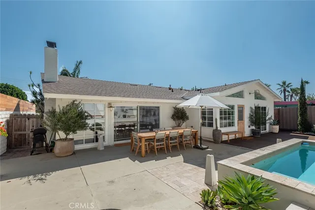 a view of a patio with couches table and chairs under an umbrella