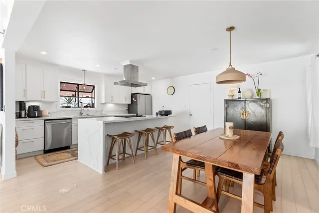 a open kitchen with stainless steel appliances granite countertop a stove a sink dishwasher and a dining table with wooden floor