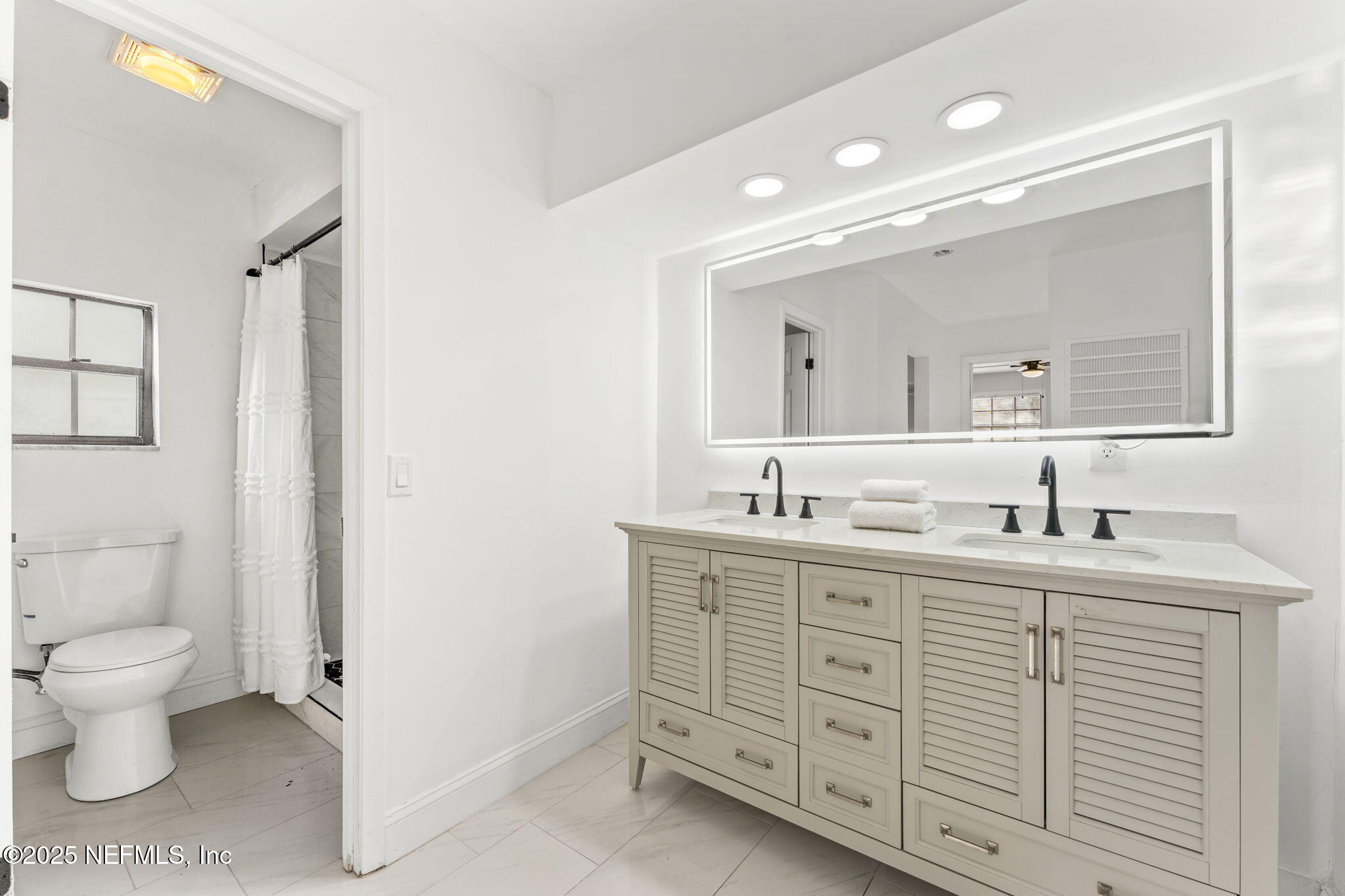 6211 Firestone Road Jacksonville, FL 32244 - Photo 27 of 41 a spacious bathroom with a double vanity sink a toilet and a mirror