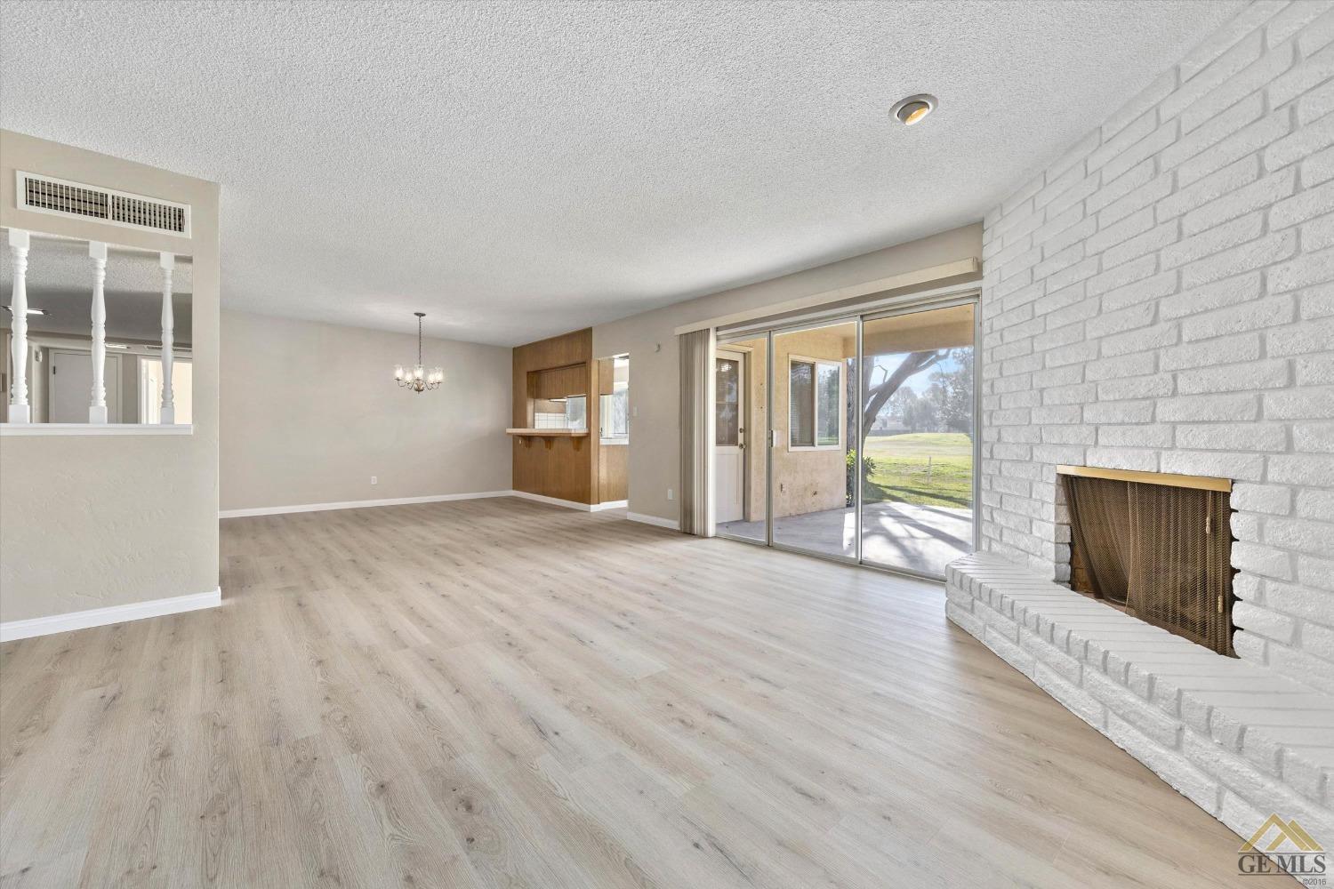 Undisclosed Address Bakersfield, CA 93309 - Photo 10 of 32 an empty room with wooden floor and fireplace