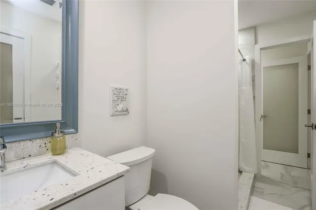 a bathroom with a granite countertop sink a toilet and a shower