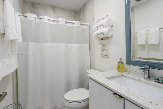a bathroom with a granite countertop sink a toilet and shower