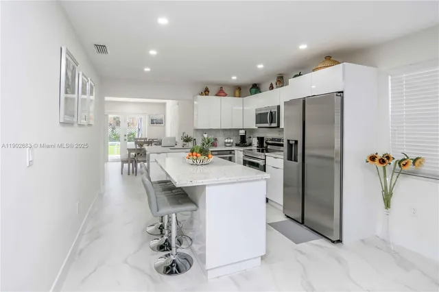a kitchen with refrigerator and chairs