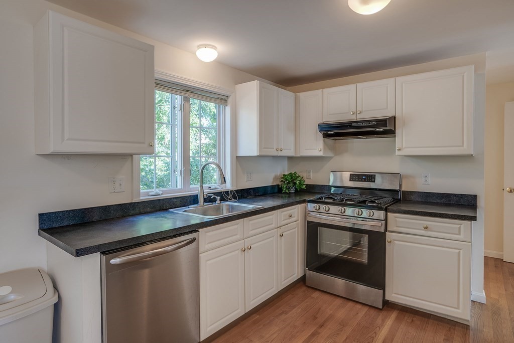 985 Trapelo Road, Unit 22 Waltham, MA 02452 - Photo 3 of 29 a kitchen with stainless steel appliances granite countertop a sink stove and white cabinets