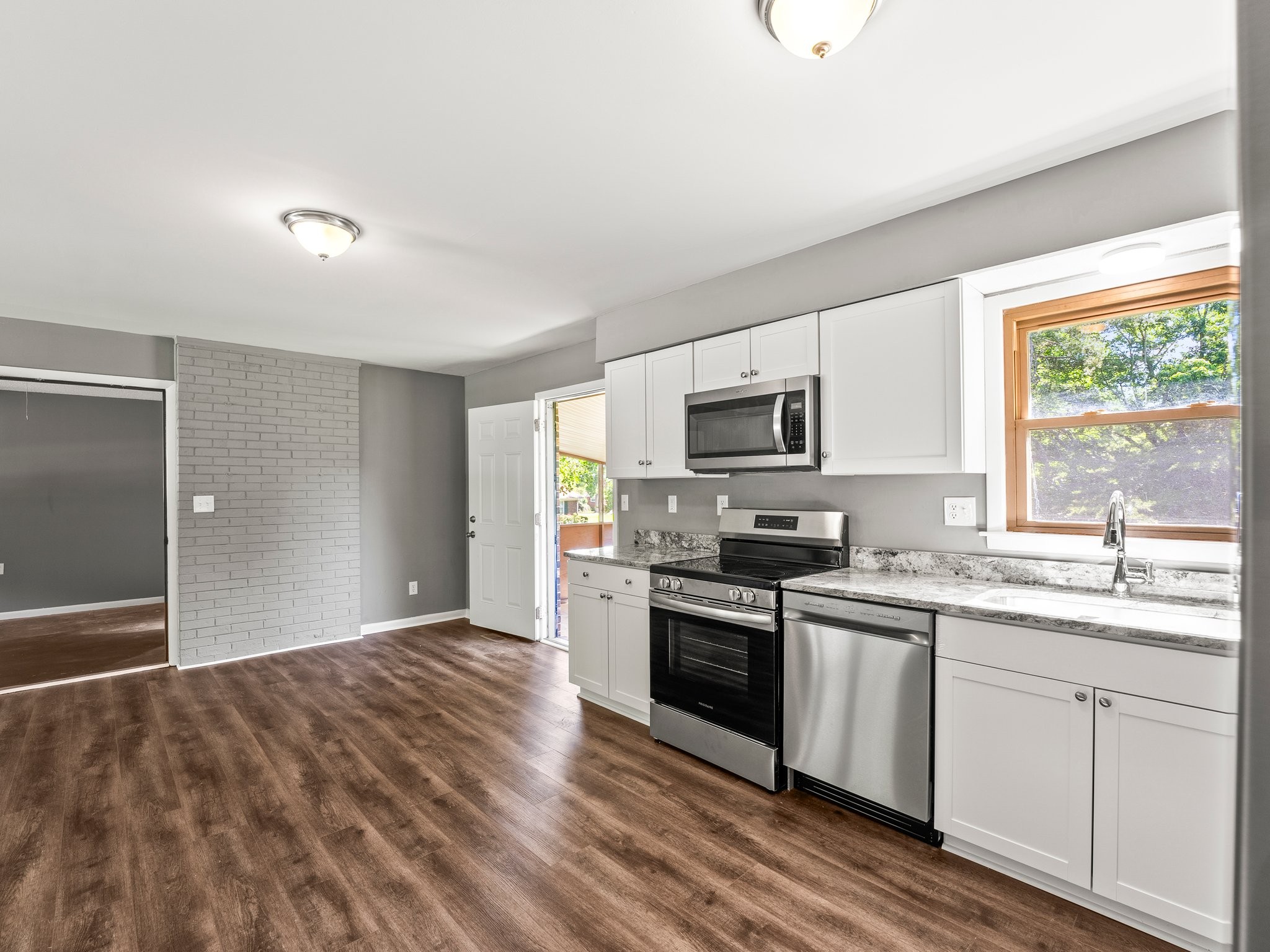 103 Cedar Street Huntland, TN 37345 - Photo 14 of 26 a kitchen with stainless steel appliances granite countertop a stove top oven a sink dishwasher and a refrigerator with wooden floor
